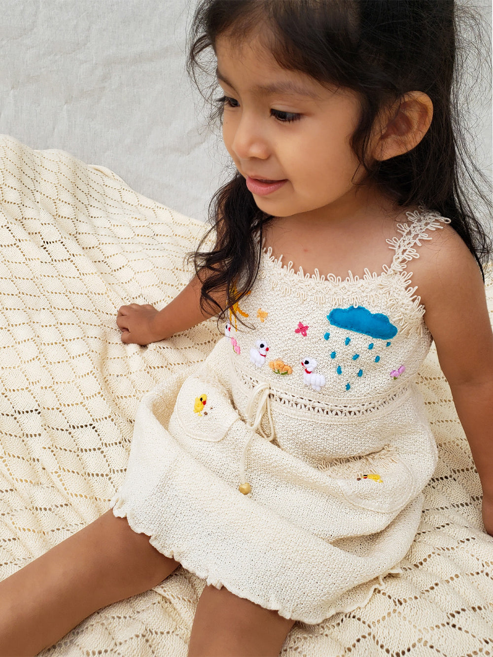 Liten Aventuris Collections. Dress your little star in this Estrella Dress! Featuring a strappy design, two front pockets with intricate cotton knitted lace, and colorful farm animal embroidery, your kiddo will be twinkling bright in no time! With its natural Peruvian Tanguis Cotton and star-inspired name, this dress will make your kids feel like they have the universe in their pocket! Ethically made in Peru. Ekologisk klänning för flickor och bebisar.