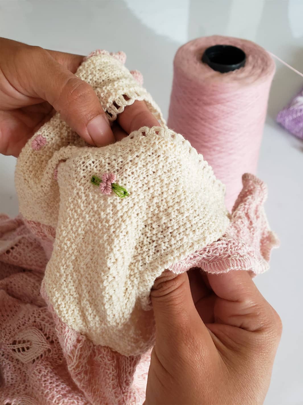 Hand embroidering a delicate flower on a knitted Tanguis cotton dress by Liten Aventuris, highlighting our artisanal work. | Handbrodering av en delikat blomma på en stickad Tanguis-bomullklänning från Liten Aventuris, som framhäver hantverksmässigan. | Bordado a mano de una delicada flor en un vestido de algodón Tanguis tejido de Liten Aventuris, resaltando lo artesanal.