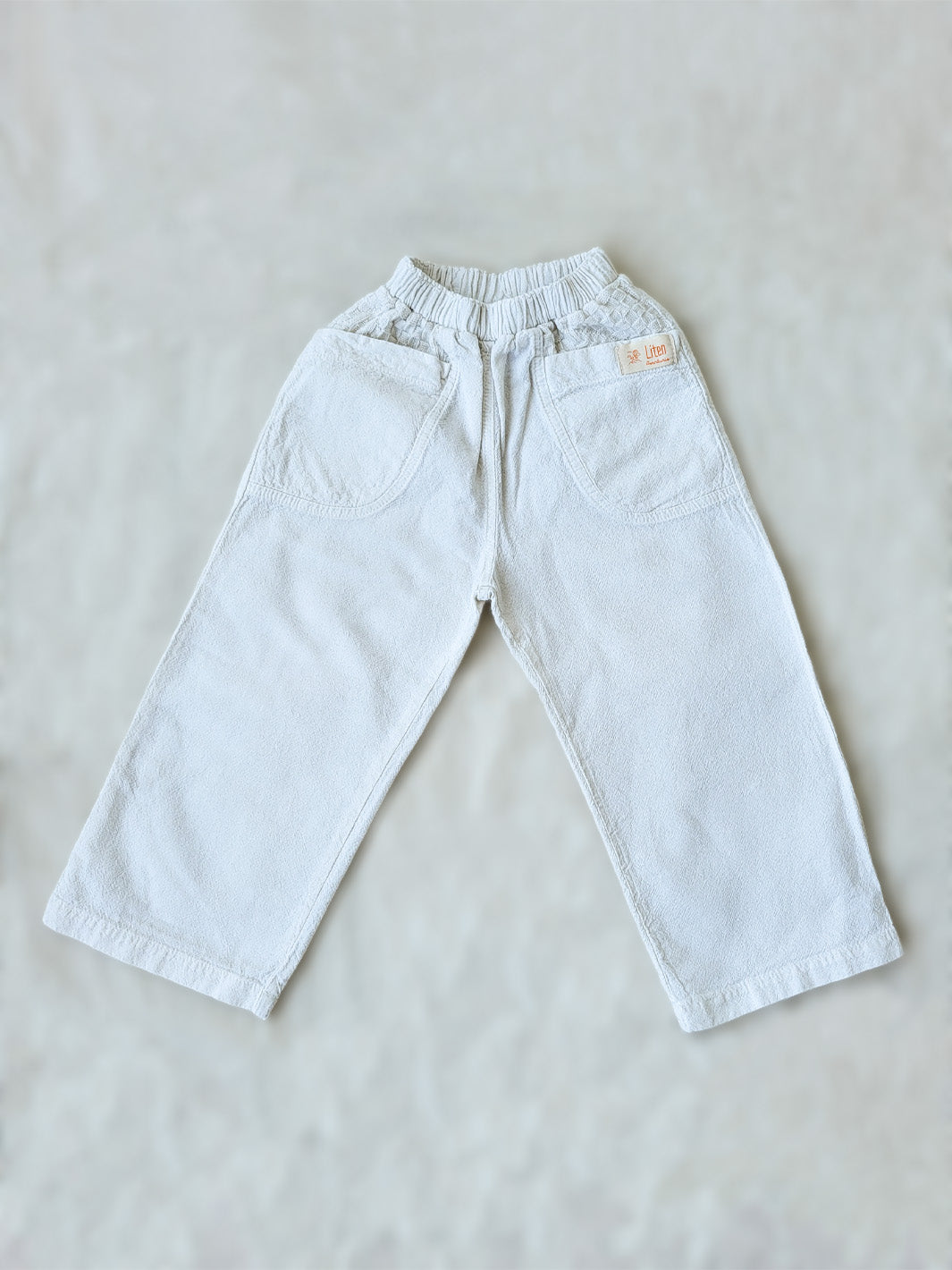 The Olve pants are light and very comfortable. Excellent for traveling or playing outside! These loose-fit pants provide freedom of movement. And the lateral pockets at the front are internally layered with a knitted-cotton pattern. This gives the perfect artisanal touch. Mix and match different outfits with any top from any of our Liten Aventuris collections. Unisex cotton pants. Barnkläder, Bomullskläder, Natural kläder. Flicka, pojken och babis kläder. Barn Byxor.