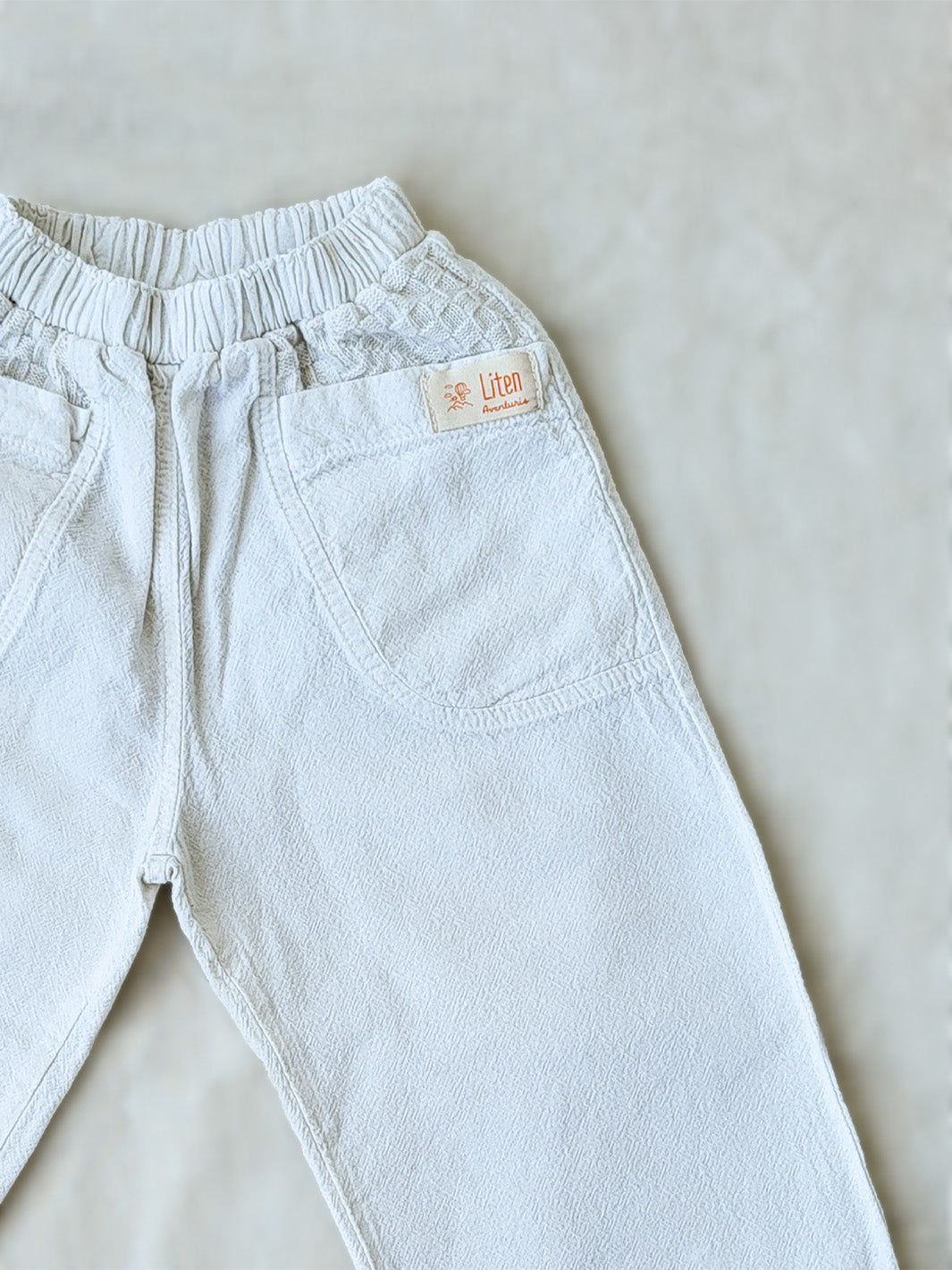 The Olve pants are light and very comfortable. Excellent for traveling or playing outside! These loose-fit pants provide freedom of movement. And the lateral pockets at the front are internally layered with a knitted-cotton pattern. This gives the perfect artisanal touch. Mix and match different outfits with any top from any of our Liten Aventuris collections. Unisex cotton pants. Barnkläder, Bomullskläder, Natural kläder. Flicka, pojken och babis kläder. Barn Byxor.