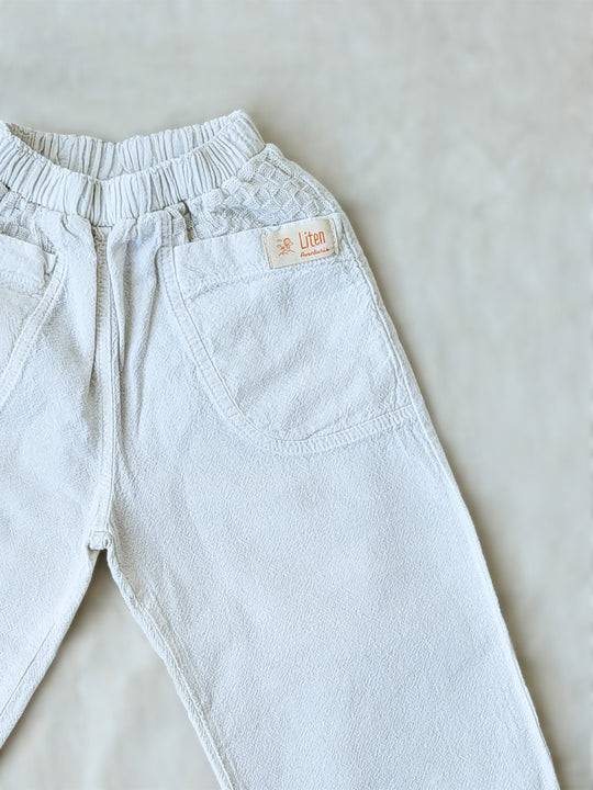 The Olve pants are light and very comfortable. Excellent for traveling or playing outside! These loose-fit pants provide freedom of movement. And the lateral pockets at the front are internally layered with a knitted-cotton pattern. This gives the perfect artisanal touch. Mix and match different outfits with any top from any of our Liten Aventuris collections. Unisex cotton pants. Barnkläder, Bomullskläder, Natural kläder. Flicka, pojken och babis kläder. Barn Byxor.