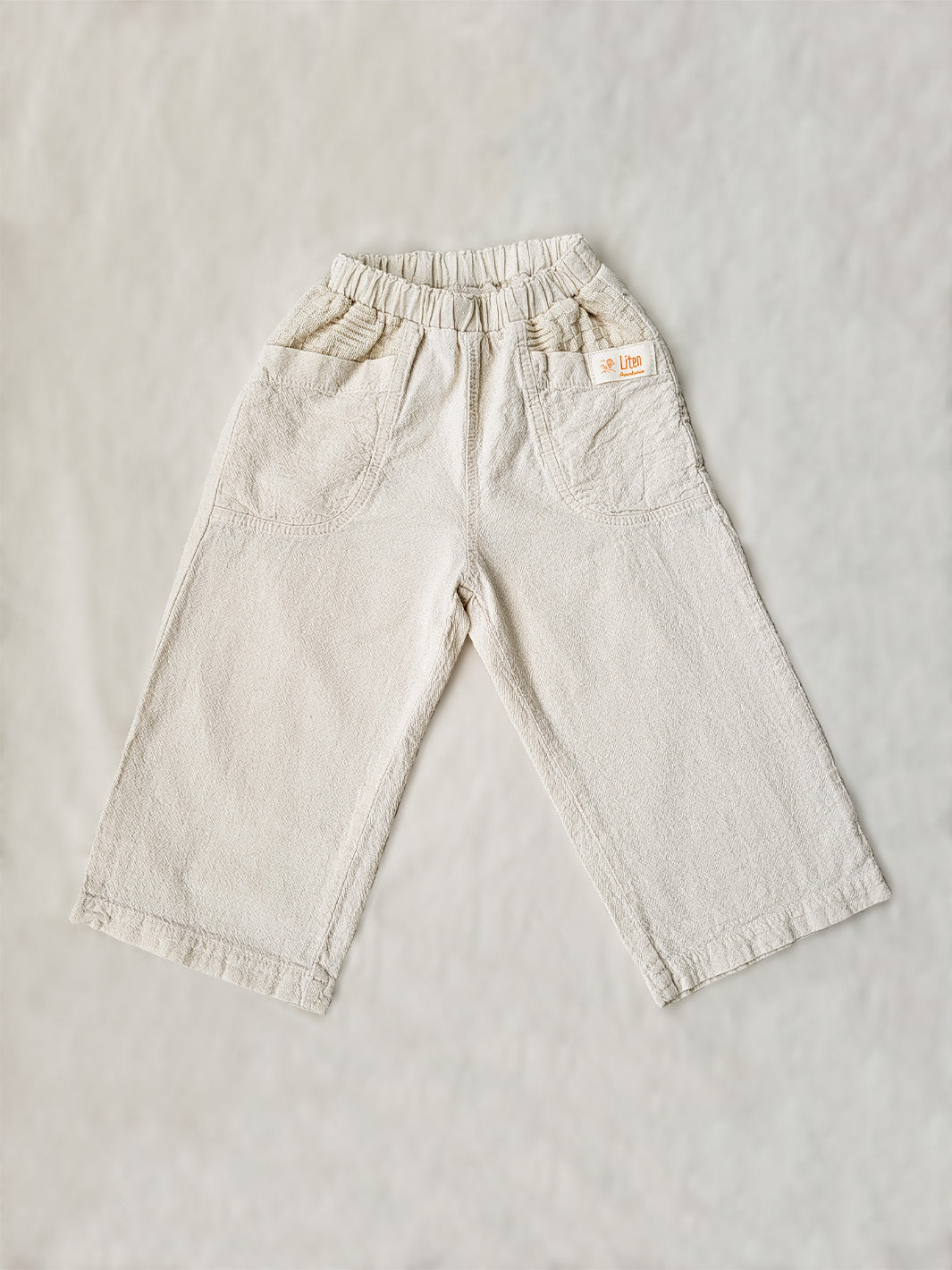 The Olve pants are light and very comfortable. Excellent for traveling or playing outside! These loose-fit pants provide freedom of movement. And the lateral pockets at the front are internally layered with a knitted-cotton pattern. This gives the perfect artisanal touch. Mix and match different outfits with any top from any of our Liten Aventuris collections. Unisex cotton pants. Barnkläder, Bomullskläder, Natural kläder. Flicka, pojken och babis kläder. Barn Byxor.