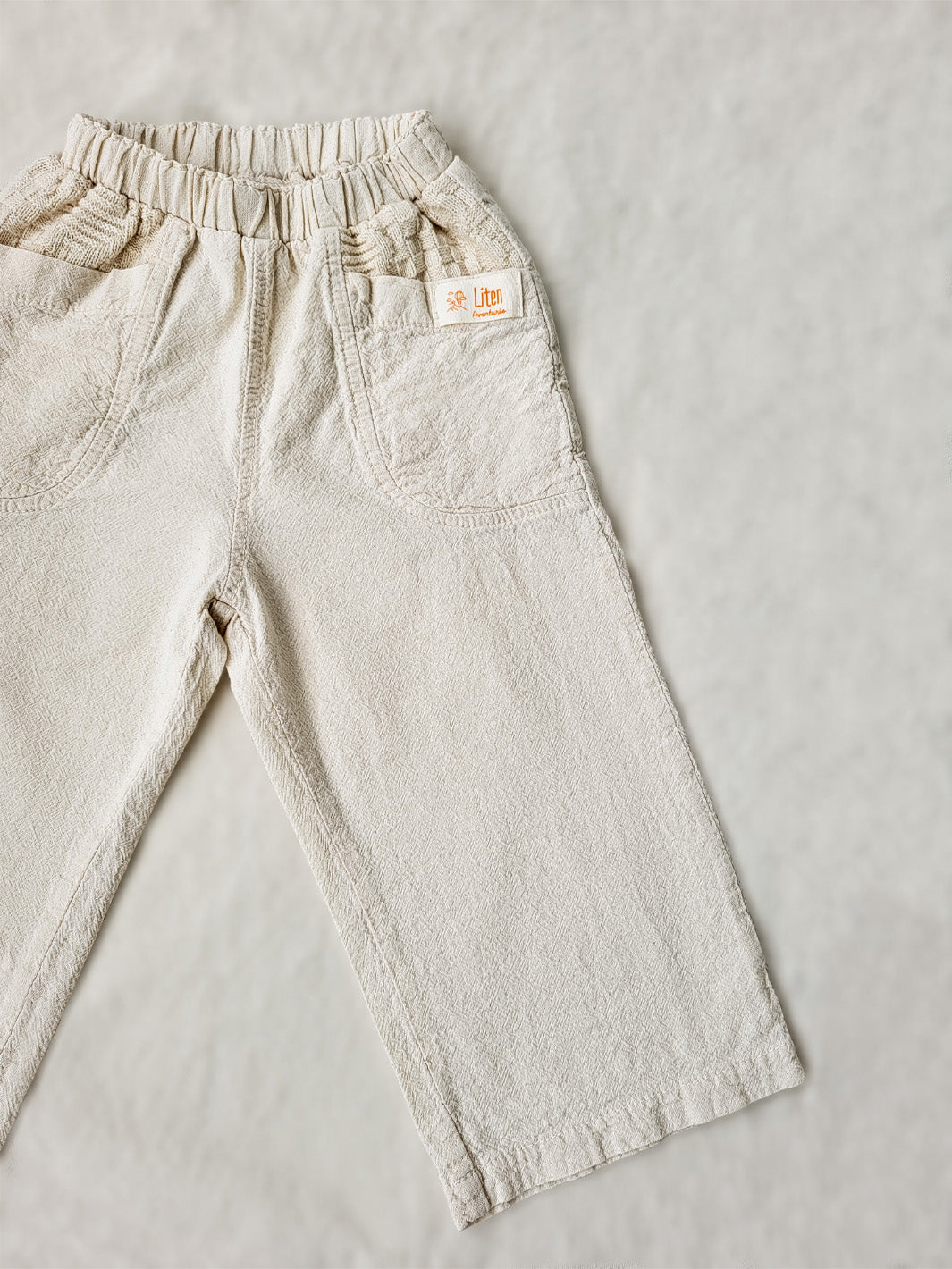 The Olve pants are light and very comfortable. Excellent for traveling or playing outside! These loose-fit pants provide freedom of movement. And the lateral pockets at the front are internally layered with a knitted-cotton pattern. This gives the perfect artisanal touch. Mix and match different outfits with any top from any of our Liten Aventuris collections. Unisex cotton pants. Barnkläder, Bomullskläder, Natural kläder. Flicka, pojken och babis kläder. Barn Byxor.