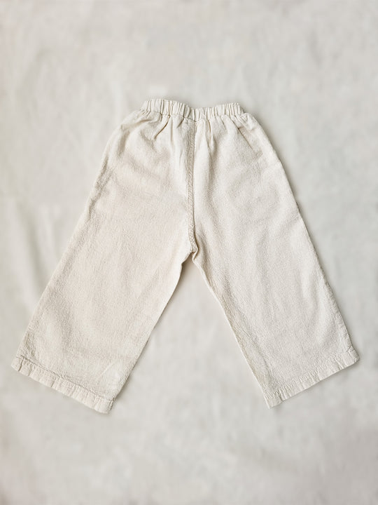 The Olve pants are light and very comfortable. Excellent for traveling or playing outside! These loose-fit pants provide freedom of movement. And the lateral pockets at the front are internally layered with a knitted-cotton pattern. This gives the perfect artisanal touch. Mix and match different outfits with any top from any of our Liten Aventuris collections. Unisex cotton pants. Barnkläder, Bomullskläder, Natural kläder. Flicka, pojken och babis kläder. Barn Byxor.
