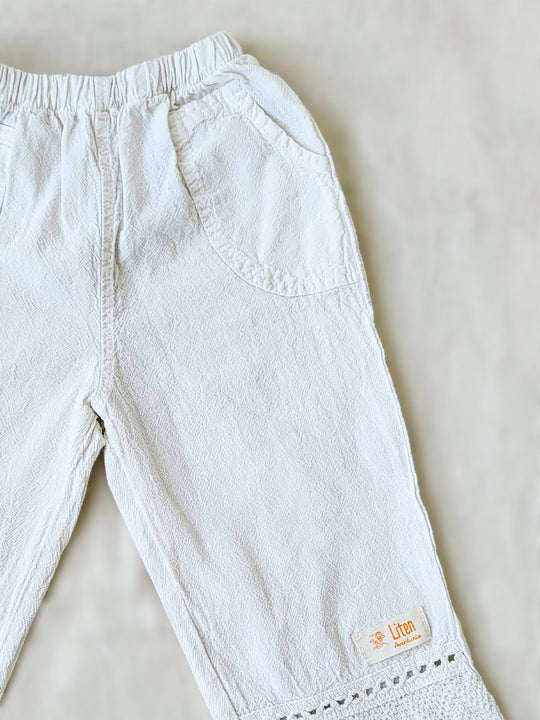 Liten Aventuris brand. Keep your little girl comfy and stylish in our Annie Pants! These natural cotton pants feature playful knitted cotton patterns at the bottom for added breeziness. With front pockets for keeping those special treasures! The soft material will keep your young one feeling silky. Pair this loose-fitting design with our Annie Blouse for the perfect winning combo! Flickan Byxor, Barns bomullskläder, svenska kläder, flickans byxor, ekologisk kläder, babis byxor.