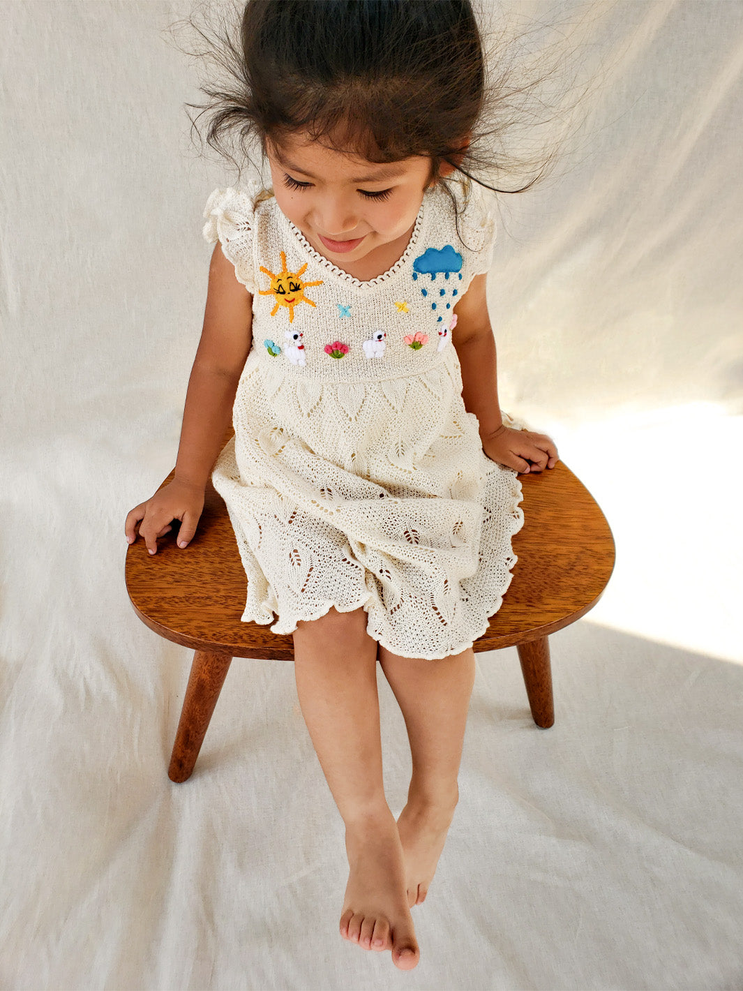 Explore the wild outdoors with your little one in the Pia Dress. Hand-embroidered with colorful designs inspired by farm animals and nature. Its cap sleeves and button behind the neck allow the perfect fit. This unique piece will spark your little one's imagination! A truly artisanal piece, with its natural cotton knitted pattern inspired by leaves and its inner layer in jersey cotton! Ekologisk klänning för flickor och bebisar.