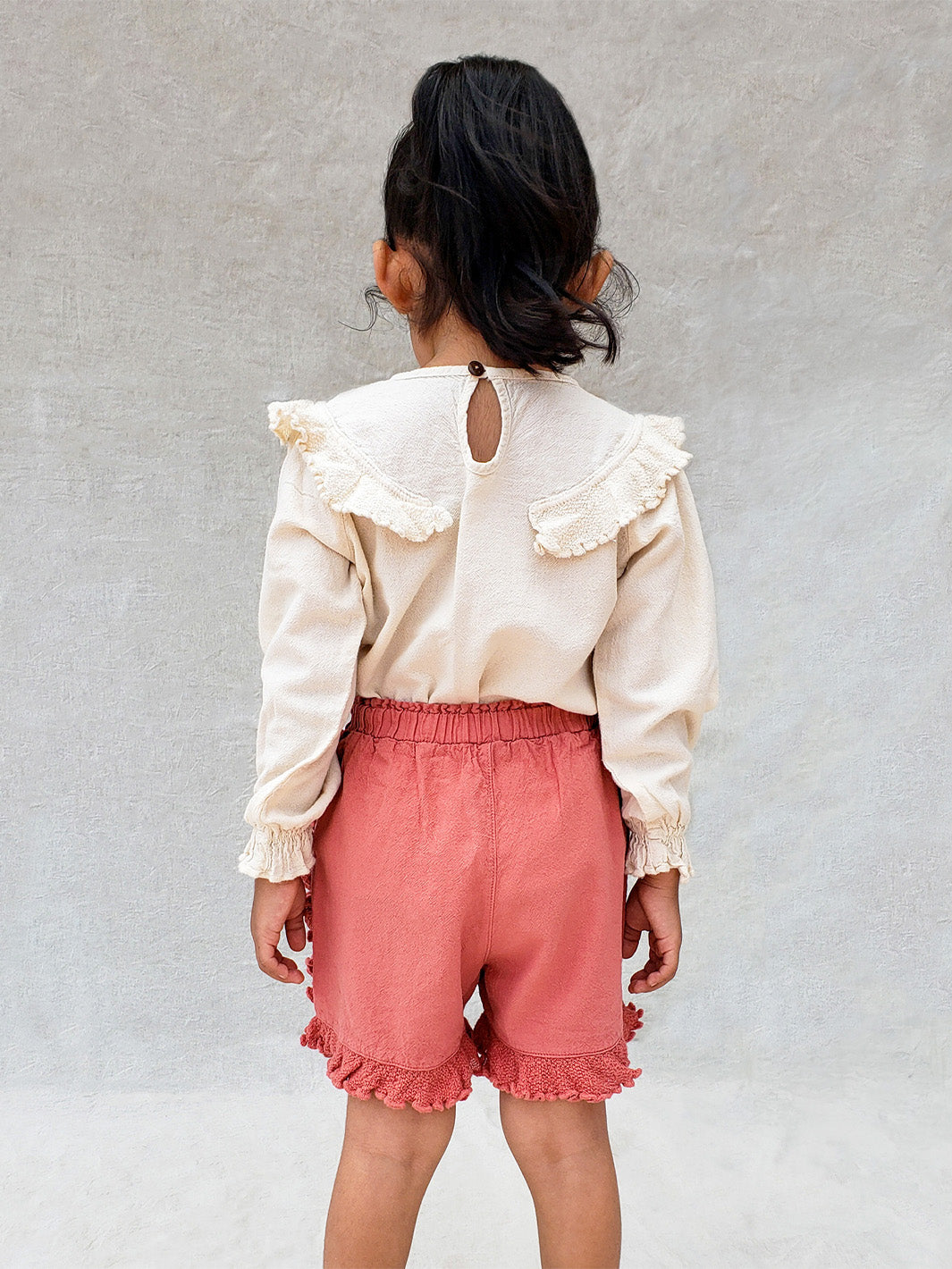 Liten Aventuris. Our Siri Blouse is elegant and comfortable at the same time. Its long sleeves with ruffles on the wrists are perfect for an evening stroll. The knitted cotton ruffles on the chest add a nice artisanal touch. Part of our Collection. Loose-fitting garment. 100% Flat-knitted Natural Peruvian Tocuyo Cotton. 100% knitted Natural Tanguis Cotton. Ethically made in Peru. Perfect for girls. Barnkläder, Bomullskläder, Natural kläder. Flicka kläder. Flickblus. Barnblus.
