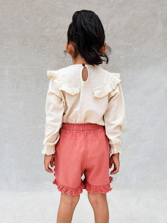 Liten Aventuris. Our Siri Blouse is elegant and comfortable at the same time. Its long sleeves with ruffles on the wrists are perfect for an evening stroll. The knitted cotton ruffles on the chest add a nice artisanal touch. Part of our Collection. Loose-fitting garment. 100% Flat-knitted Natural Peruvian Tocuyo Cotton. 100% knitted Natural Tanguis Cotton. Ethically made in Peru. Perfect for girls. Barnkläder, Bomullskläder, Natural kläder. Flicka kläder. Flickblus. Barnblus.