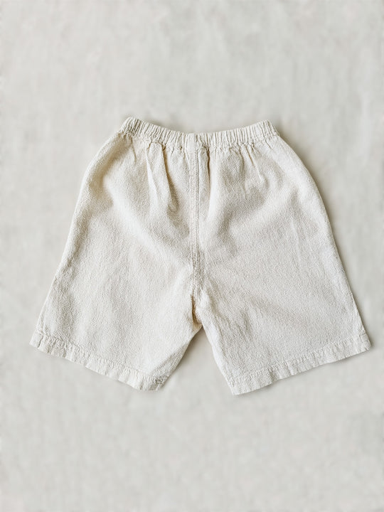 Liten Aventuris Natural Tocuyo Cotton shorts for kids. Our Niko shorts are perfect for exploring outside. With its loose-fitting size and soft elastic on the waist, toddlers and kids will feel comfortable and free. Perfect for boys and girls. Barnkläder, Bomullskläder, Natural kläder. Flicka och pojken kläder. Barn kortbyxor, byxor, .byxa.