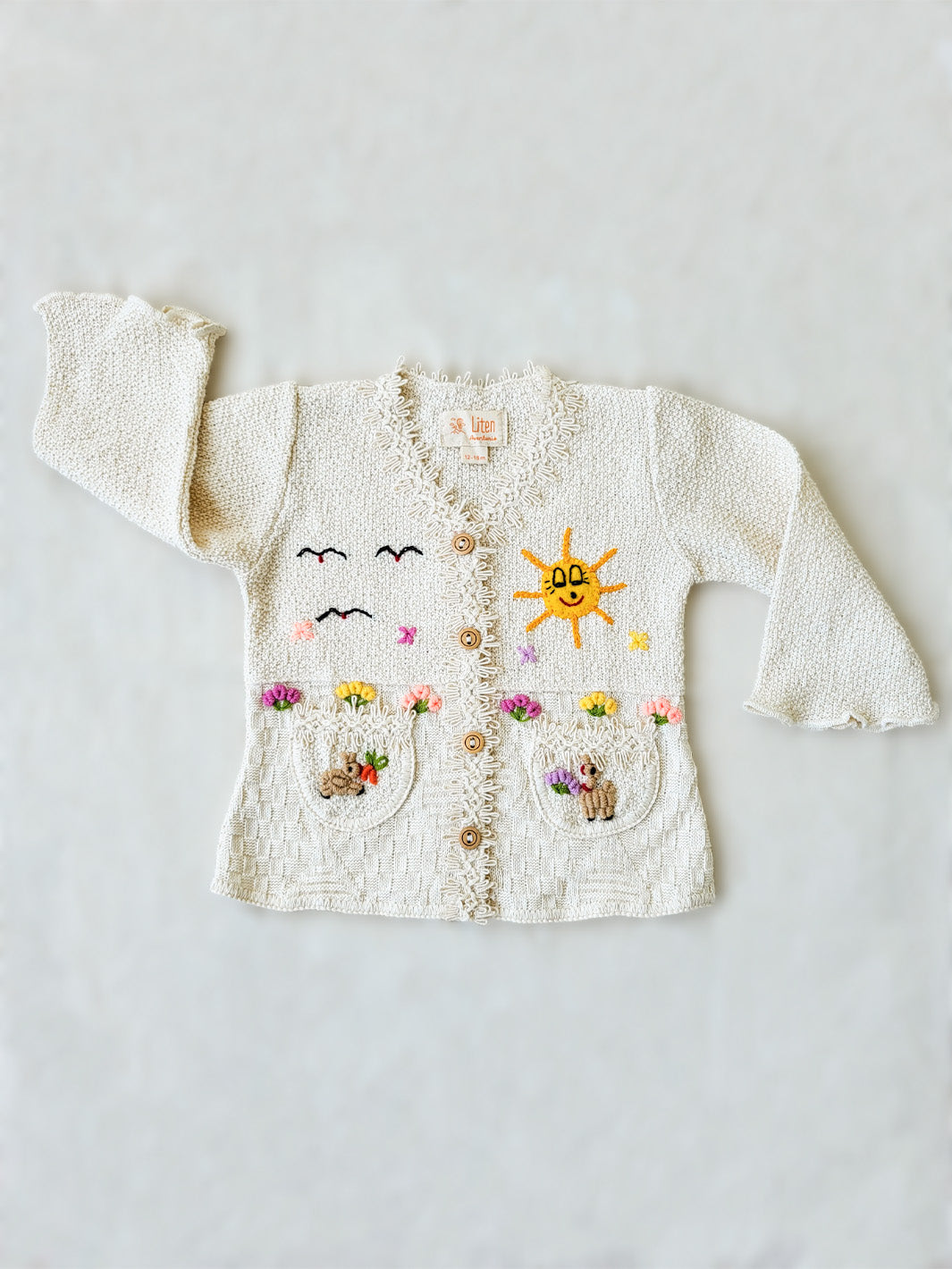 This Sandy Jacket is perfect for your little one's outdoor adventures! Our loose-fit jacket has hand-embroidered farm animals, flowers, and other nature-inspired design elements to give your stylish kid an extra-special look. Plus, two front pockets, and wooden buttons just for fun. Crafted with a combination of regular and geometrical knitted patterns. Liten Aventuris collections. Handbroderade barnkläder, Bomullsjacka, Barnjacka, Babyjacka.
