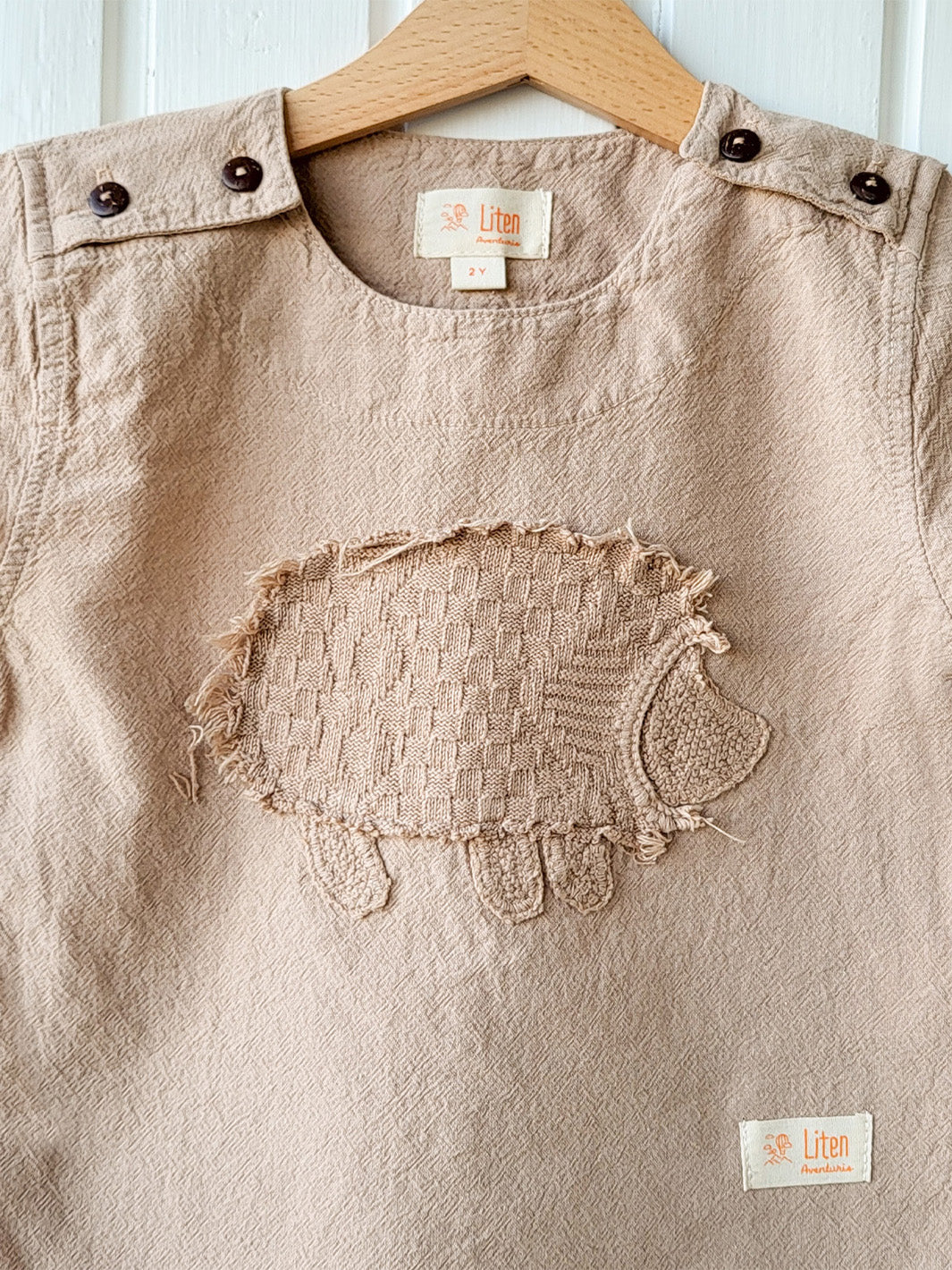 Liten Aventuris Natural Tocuyo Cotton t-shirt for kids. Kirpi is a cute little porcupine embroidered in knitted natural tanguis cotton. Our skilled artisans handcrafted Kirpi with care and attention to detail. Our lovely Kirpi T-shirt is a loose-fitting garment with coconut buttons. The opening on the shoulders makes the kid more comfortable when dressing up. Ethically made in Peru. Bomullskläder, barnkläder, Pojken & flickan tröja, Natural kläder, ekologisk kläder. Skjortor.