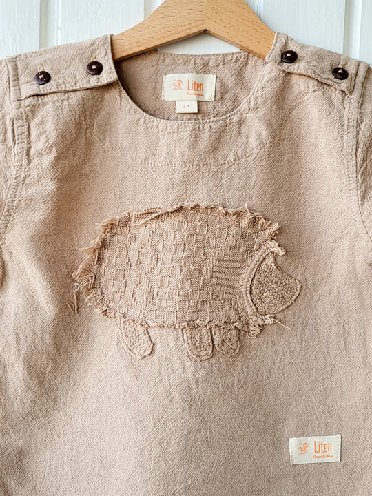 Liten Aventuris Natural Tocuyo Cotton t-shirt for kids. Kirpi is a cute little porcupine embroidered in knitted natural tanguis cotton. Our skilled artisans handcrafted Kirpi with care and attention to detail. Our lovely Kirpi T-shirt is a loose-fitting garment with coconut buttons. The opening on the shoulders makes the kid more comfortable when dressing up. Ethically made in Peru. Bomullskläder, barnkläder, Pojken & flickan tröja, Natural kläder, ekologisk kläder. Skjortor.