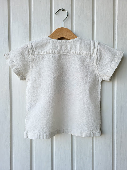 Liten Aventuris Natural Tocuyo Cotton t-shirt for kids. Kirpi is a cute little porcupine embroidered in knitted natural tanguis cotton. Our skilled artisans handcrafted Kirpi with care and attention to detail. Our lovely Kirpi T-shirt is a loose-fitting garment with coconut buttons. The opening on the shoulders makes the kid more comfortable when dressing up. Ethically made in Peru. Bomullskläder, barnkläder, Pojken & flickan tröja, Natural kläder, ekologisk kläder. Skjortor.