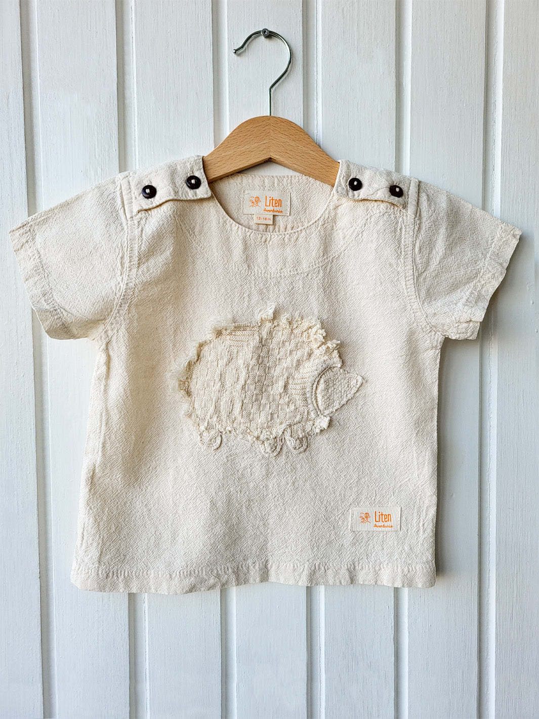 Liten Aventuris Natural Tocuyo Cotton t-shirt for kids. Kirpi is a cute little porcupine embroidered in knitted natural tanguis cotton. Our skilled artisans handcrafted Kirpi with care and attention to detail. Our lovely Kirpi T-shirt is a loose-fitting garment with coconut buttons. The opening on the shoulders makes the kid more comfortable when dressing up. Ethically made in Peru. Bomullskläder, barnkläder, Pojken & flickan tröja, Natural kläder, ekologisk kläder. Skjortor.