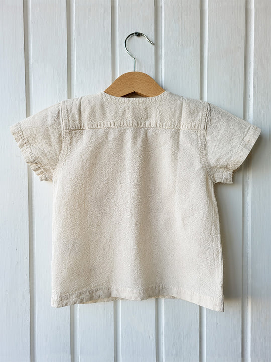 Liten Aventuris Natural Tocuyo Cotton t-shirt for kids. Kirpi is a cute little porcupine embroidered in knitted natural tanguis cotton. Our skilled artisans handcrafted Kirpi with care and attention to detail. Our lovely Kirpi T-shirt is a loose-fitting garment with coconut buttons. The opening on the shoulders makes the kid more comfortable when dressing up. Ethically made in Peru. Bomullskläder, barnkläder, Pojken & flickan tröja, Natural kläder, ekologisk kläder. Skjortor.