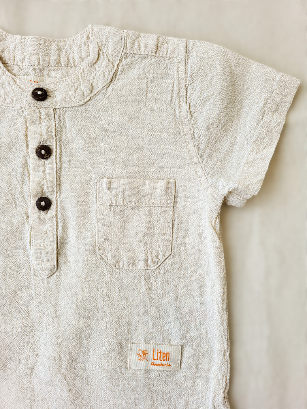 Liten Aventuris Natural Tocuyo Cotton shirt for kids. The Philipo shirt is perfect for a picnic at a lake or a nice morning stroll! This short sleeve shirt with coconut buttons and tunisian collar is casual and chic at the same time. This loose-fitting shirt with one pocket, is comfortable and soft with the skin. Ethically made in Peru. Bomullskläder, barnkläder, Pojken tröja, Natural kläder, ekologisk kläder.