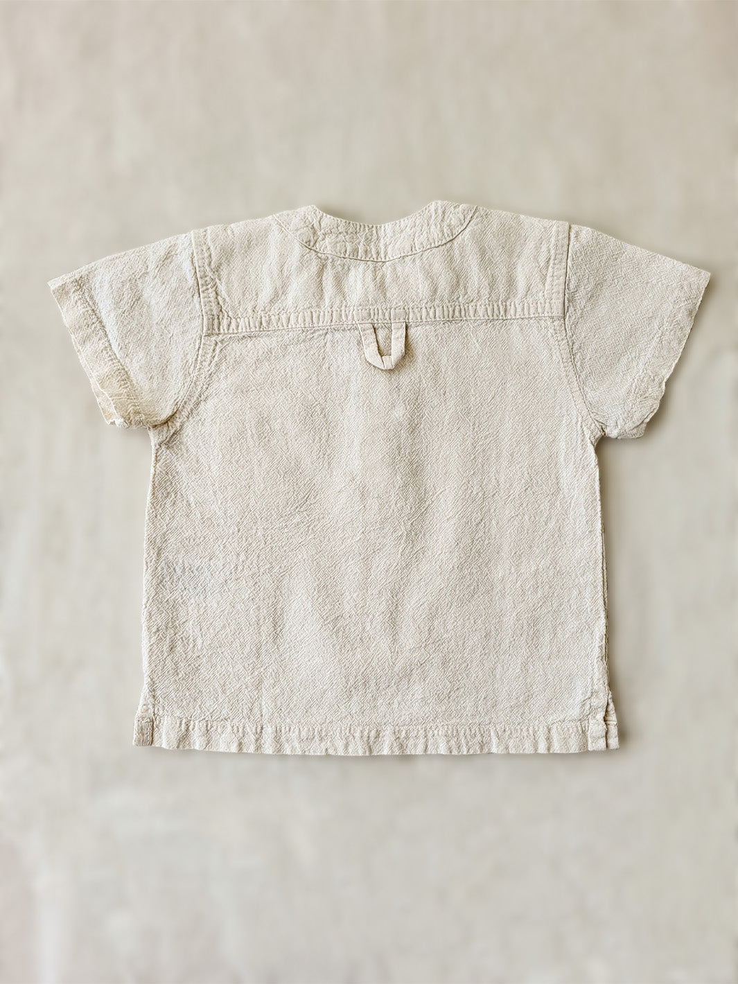 Liten Aventuris Natural Tocuyo Cotton shirt for kids. The Philipo shirt is perfect for a picnic at a lake or a nice morning stroll! This short sleeve shirt with coconut buttons and tunisian collar is casual and chic at the same time. This loose-fitting shirt with one pocket, is comfortable and soft with the skin. Ethically made in Peru. Bomullskläder, barnkläder, Pojken tröja, Natural kläder, ekologisk kläder.
