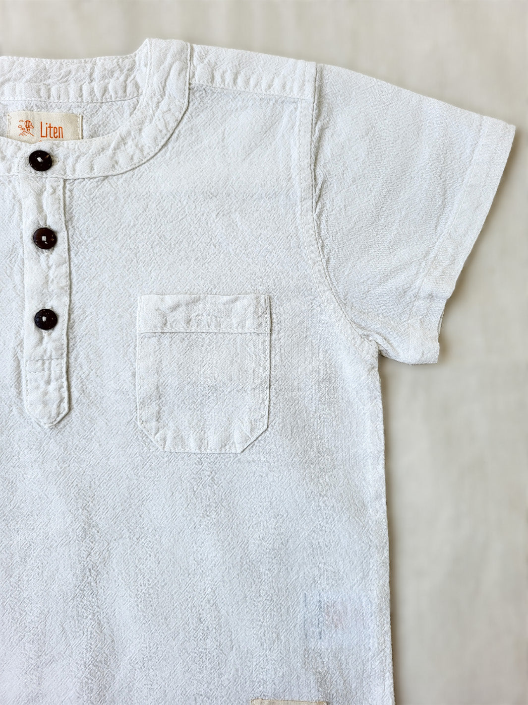 Liten Aventuris Natural Tocuyo Cotton shirt for kids. The Philipo shirt is perfect for a picnic at a lake or a nice morning stroll! This short sleeve shirt with coconut buttons and tunisian collar is casual and chic at the same time. This loose-fitting shirt with two pockets, is comfortable and soft with the skin. Ethically made in Peru. Bomullskläder, barnkläder, Pojken tröja, Natural kläder, ekologisk kläder. Skjortor.