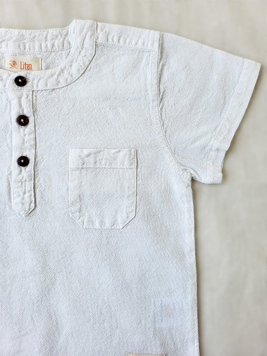 Liten Aventuris Natural Tocuyo Cotton shirt for kids. The Philipo shirt is perfect for a picnic at a lake or a nice morning stroll! This short sleeve shirt with coconut buttons and tunisian collar is casual and chic at the same time. This loose-fitting shirt with two pockets, is comfortable and soft with the skin. Ethically made in Peru. Bomullskläder, barnkläder, Pojken tröja, Natural kläder, ekologisk kläder. Skjortor.
