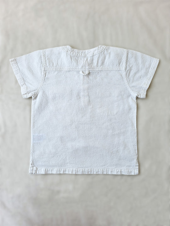 Liten Aventuris Natural Tocuyo Cotton shirt for kids. The Philipo shirt is perfect for a picnic at a lake or a nice morning stroll! This short sleeve shirt with coconut buttons and tunisian collar is casual and chic at the same time. This loose-fitting shirt with two pockets, is comfortable and soft with the skin. Ethically made in Peru. Bomullskläder, barnkläder, Pojken tröja, Natural kläder, ekologisk kläder. Skjortor.