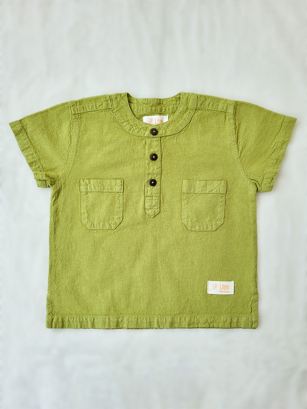 Liten Aventuris Natural Tocuyo Cotton shirt for kids. The Philipo shirt is perfect for a picnic at a lake or a nice morning stroll! This short sleeve shirt with coconut buttons and tunisian collar is casual and chic at the same time. This loose-fitting shirt with two pockets, is comfortable and soft with the skin. Ethically made in Peru. Bomullskläder, barnkläder, Pojken tröja, Natural kläder, ekologisk kläder. Skjortor.
