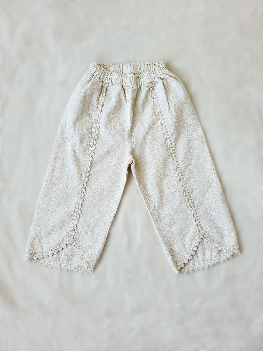 Liten Aventuris Natural Tocuyo Cotton pants for kids. Our Lorin pants are perfect for sunny days. With its loose-fitting size and soft elastic on the waist, toddlers and kids will feel comfortable and free. The Lorin pants bring an embroidered cotton decorative ribbon that will be the perfect match to our Lorin T-shirt! Perfect for girls. Barnkläder, Bomullskläder, Natural kläder. Flicka kläder. Barn Byxor.