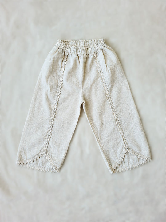 Liten Aventuris Natural Tocuyo Cotton pants for kids. Our Lorin pants are perfect for sunny days. With its loose-fitting size and soft elastic on the waist, toddlers and kids will feel comfortable and free. The Lorin pants bring an embroidered cotton decorative ribbon that will be the perfect match to our Lorin T-shirt! Perfect for girls. Barnkläder, Bomullskläder, Natural kläder. Flicka kläder. Barn Byxor.