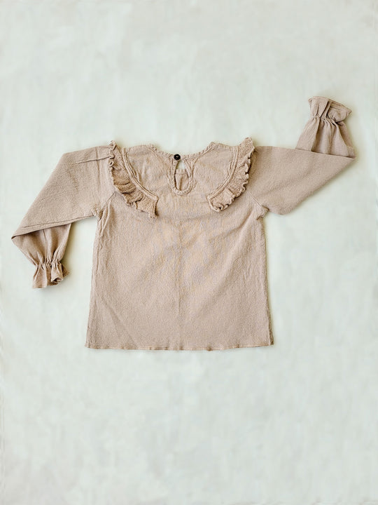Liten Aventuris. Our Siri Blouse is elegant and comfortable at the same time. Its long sleeves with ruffles on the wrists are perfect for an evening stroll. The knitted cotton ruffles on the chest add a nice artisanal touch. Part of our Collection. Loose-fitting garment. 100% Flat-knitted Natural Peruvian Tocuyo Cotton. 100% knitted Natural Tanguis Cotton. Ethically made in Peru. Perfect for girls. Barnkläder, Bomullskläder, Natural kläder. Flicka kläder. Flickblus. Barnblus.