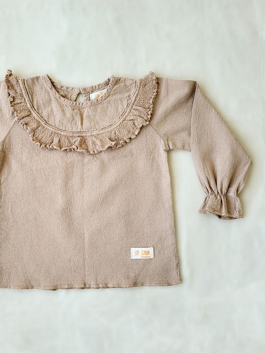 Liten Aventuris. Our Siri Blouse is elegant and comfortable at the same time. Its long sleeves with ruffles on the wrists are perfect for an evening stroll. The knitted cotton ruffles on the chest add a nice artisanal touch. Part of our Collection. Loose-fitting garment. 100% Flat-knitted Natural Peruvian Tocuyo Cotton. 100% knitted Natural Tanguis Cotton. Ethically made in Peru. Perfect for girls. Barnkläder, Bomullskläder, Natural kläder. Flicka kläder. Flickblus. Barnblus.