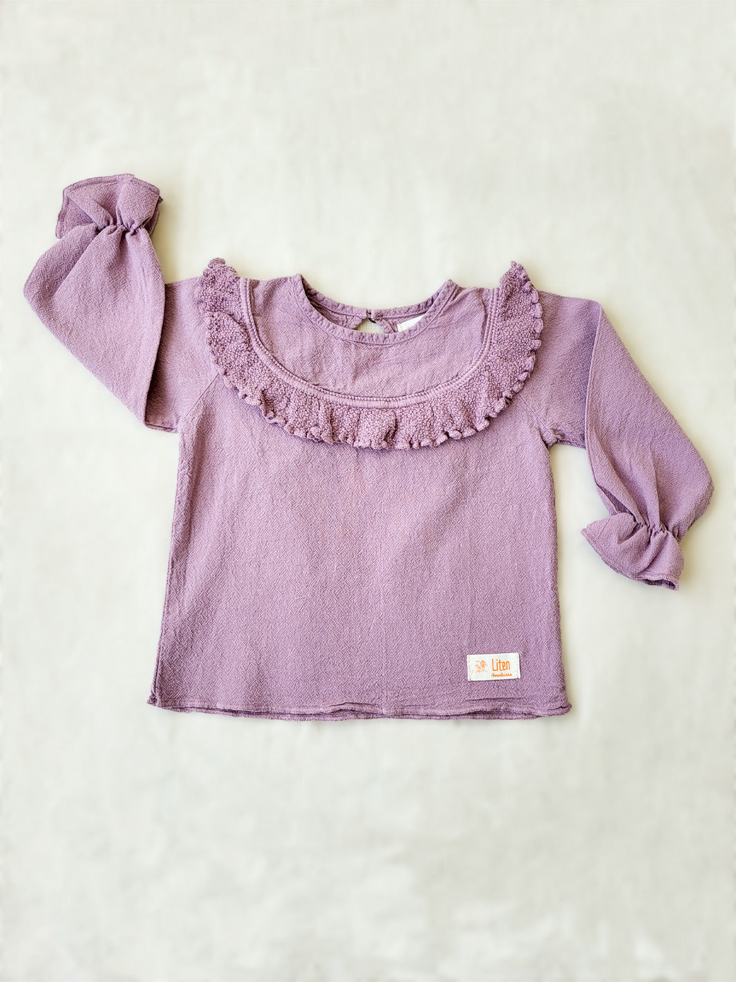 Liten Aventuris. Our Siri Blouse is elegant and comfortable at the same time. Its long sleeves with ruffles on the wrists are perfect for an evening stroll. The knitted cotton ruffles on the chest add a nice artisanal touch. Part of our Collection. Loose-fitting garment. 100% Flat-knitted Natural Peruvian Tocuyo Cotton. 100% knitted Natural Tanguis Cotton. Ethically made in Peru. Perfect for girls. Barnkläder, Bomullskläder, Natural kläder. Flicka kläder. Flickblus. Barnblus.