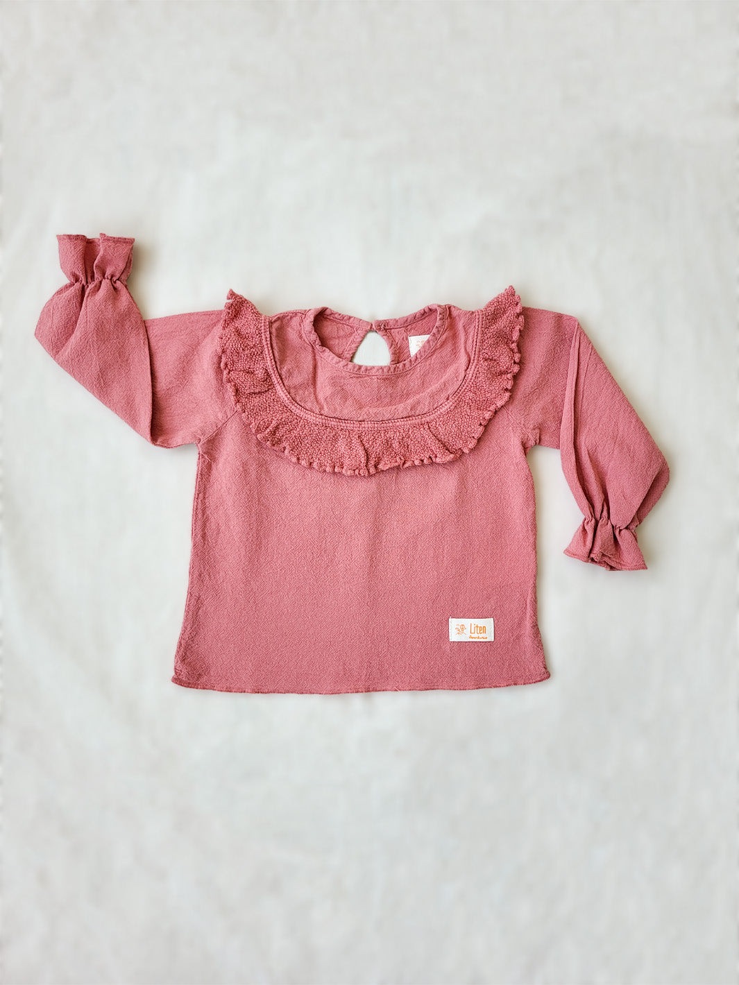 Liten Aventuris. Our Siri Blouse is elegant and comfortable at the same time. Its long sleeves with ruffles on the wrists are perfect for an evening stroll. The knitted cotton ruffles on the chest add a nice artisanal touch. Part of our Collection. Loose-fitting garment. 100% Flat-knitted Natural Peruvian Tocuyo Cotton. 100% knitted Natural Tanguis Cotton. Ethically made in Peru. Perfect for girls. Barnkläder, Bomullskläder, Natural kläder. Flicka kläder. Flickblus. Barnblus.