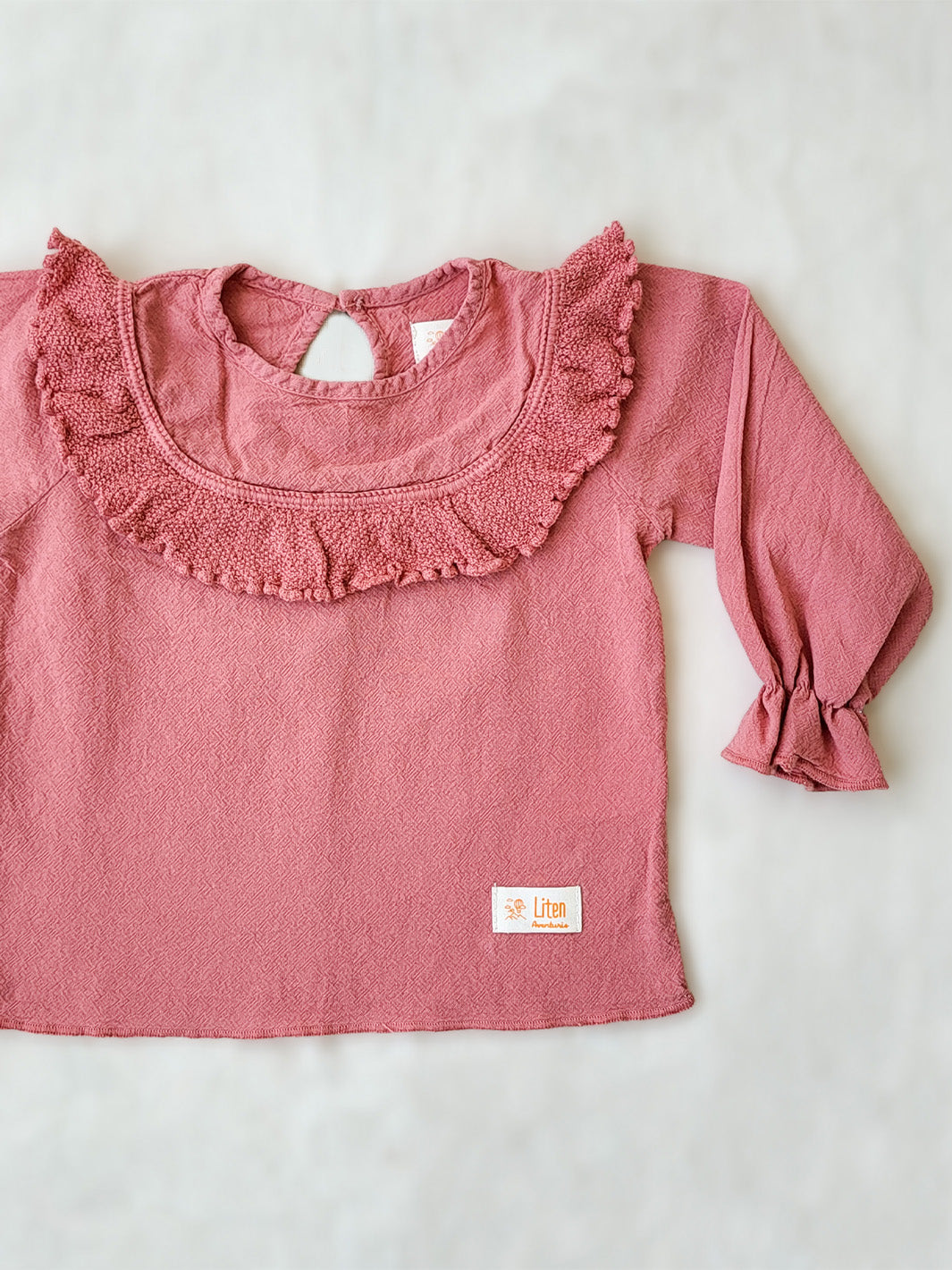 Liten Aventuris. Our Siri Blouse is elegant and comfortable at the same time. Its long sleeves with ruffles on the wrists are perfect for an evening stroll. The knitted cotton ruffles on the chest add a nice artisanal touch. Part of our Collection. Loose-fitting garment. 100% Flat-knitted Natural Peruvian Tocuyo Cotton. 100% knitted Natural Tanguis Cotton. Ethically made in Peru. Perfect for girls. Barnkläder, Bomullskläder, Natural kläder. Flicka kläder. Flickblus. Barnblus.
