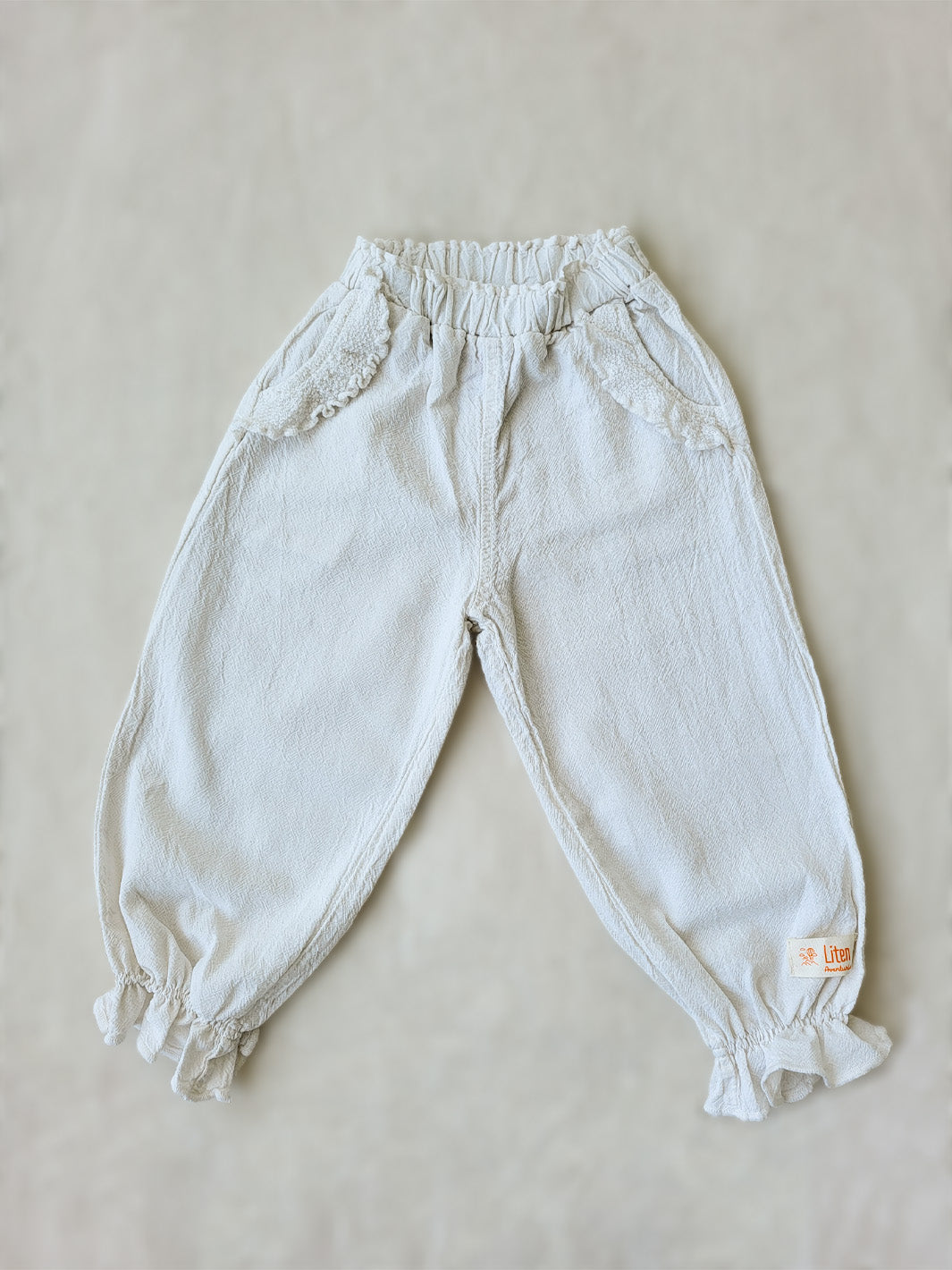 The Siri Pants are elegant and comfortable at the same time. These bloomer pants with ruffles at the bottom are perfect for a walk on the beach or a nice play date at the park. The Siri Pants bring two pockets with knitted cotton ruffles on them. It adds a nice artisanal touch. Beautiful, chic, and charming! Make the perfect match with the Siri blouse. 100% Natural Peruvian Tocuyo Cotton. Perfect for girls. Barnkläder, Bomullskläder, Natural kläder. Flicka kläder. Barn Byxor.
