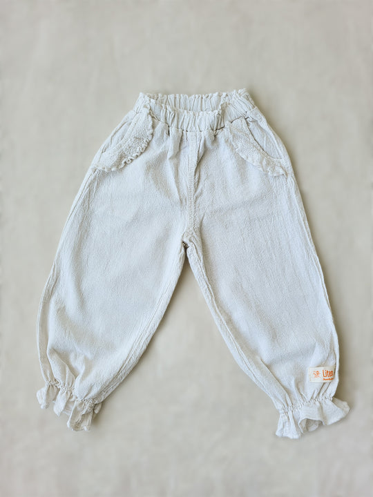 The Siri Pants are elegant and comfortable at the same time. These bloomer pants with ruffles at the bottom are perfect for a walk on the beach or a nice play date at the park. The Siri Pants bring two pockets with knitted cotton ruffles on them. It adds a nice artisanal touch. Beautiful, chic, and charming! Make the perfect match with the Siri blouse. 100% Natural Peruvian Tocuyo Cotton. Perfect for girls. Barnkläder, Bomullskläder, Natural kläder. Flicka kläder. Barn Byxor.