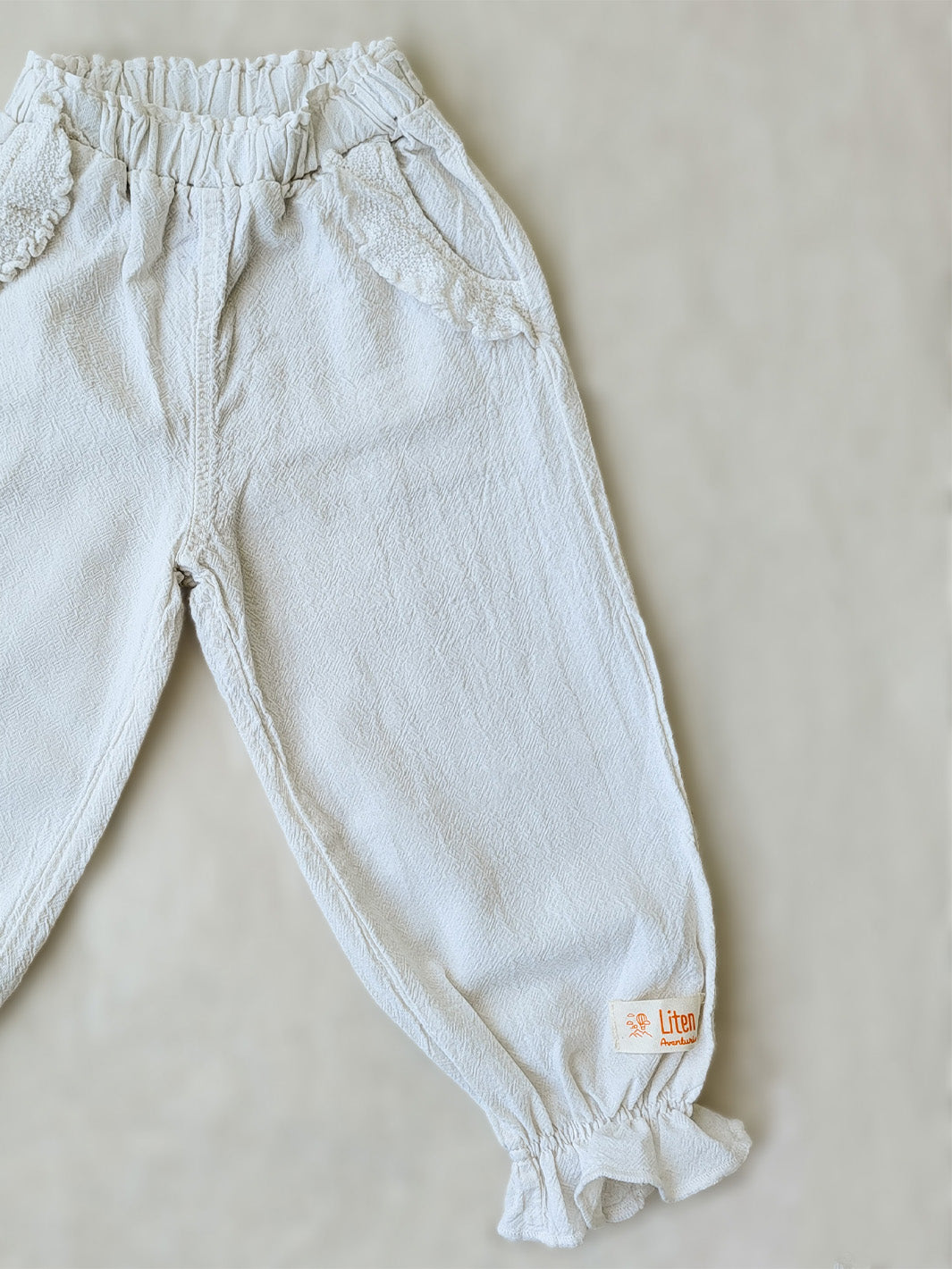The Siri Pants are elegant and comfortable at the same time. These bloomer pants with ruffles at the bottom are perfect for a walk on the beach or a nice play date at the park. The Siri Pants bring two pockets with knitted cotton ruffles on them. It adds a nice artisanal touch. Beautiful, chic, and charming! Make the perfect match with the Siri blouse. 100% Natural Peruvian Tocuyo Cotton. Perfect for girls. Barnkläder, Bomullskläder, Natural kläder. Flicka kläder. Barn Byxor.