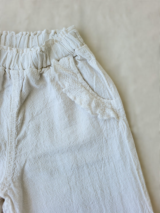 The Siri Pants are elegant and comfortable at the same time. These bloomer pants with ruffles at the bottom are perfect for a walk on the beach or a nice play date at the park. The Siri Pants bring two pockets with knitted cotton ruffles on them. It adds a nice artisanal touch. Beautiful, chic, and charming! Make the perfect match with the Siri blouse. 100% Natural Peruvian Tocuyo Cotton. Perfect for girls. Barnkläder, Bomullskläder, Natural kläder. Flicka kläder. Barn Byxor.