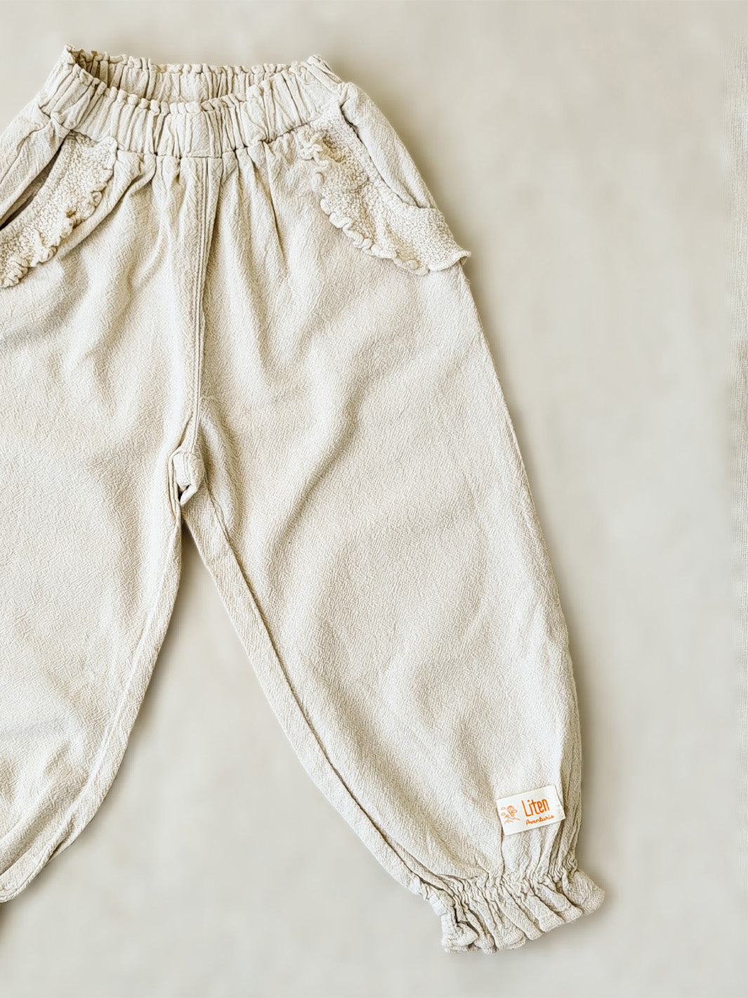 The Siri Pants are elegant and comfortable at the same time. These bloomer pants with ruffles at the bottom are perfect for a walk on the beach or a nice play date at the park. The Siri Pants bring two pockets with knitted cotton ruffles on them. It adds a nice artisanal touch. Beautiful, chic, and charming! Make the perfect match with the Siri blouse. 100% Natural Peruvian Tocuyo Cotton. Perfect for girls. Barnkläder, Bomullskläder, Natural kläder. Flicka kläder. Barn Byxor.