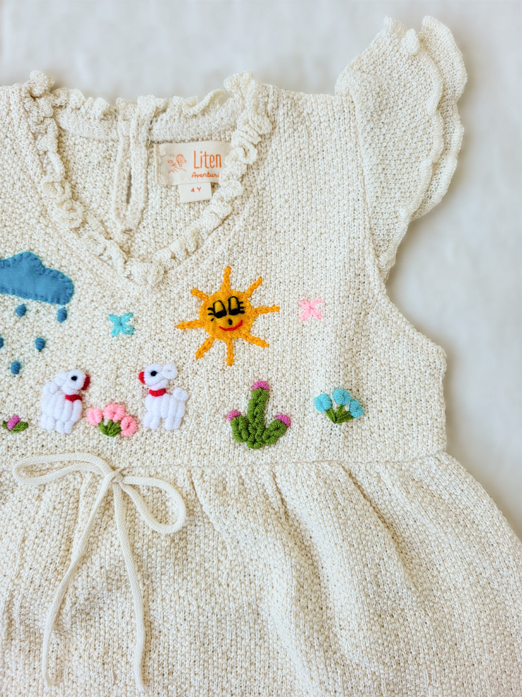 Liten Aventuris Collections. A dream fit for your little girl! Our Tanya Dress has an A-line fit and fun double-layer butterfly sleeves perfect for twirling and dancing. Made of knitted cotton fabric with hand embroidery inspired by nature. Embroidered by Peruvian artisans, this dress brings a touch of whimsy with its decorative fringe. Let your little one explore the world in style! Bomullsklänning för babis och flickor.