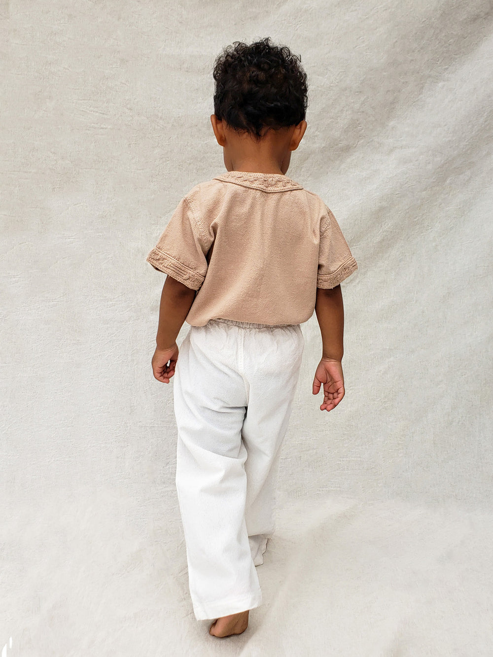 The wide-fit short sleeve Marco shirt is great for adventures! With its Tunisian collar covered in coconut buttons and decorative knitted cotton pattern, this shirt is perfect for chic and casual summer days. This bonny shirt has a front pocket where kids can save their most valuable treasures. Liten Aventuris. Ethically made in Peru. Bomullskläder, barnkläder, Pojken tröja, Skjortor, Natural kläder, ekologisk kläder.
