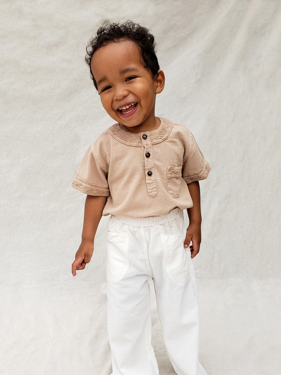 The wide-fit short sleeve Marco shirt is great for adventures! With its Tunisian collar covered in coconut buttons and decorative knitted cotton pattern, this shirt is perfect for chic and casual summer days. This bonny shirt has a front pocket where kids can save their most valuable treasures. Liten Aventuris. Ethically made in Peru. Bomullskläder, barnkläder, Pojken tröja, Skjortor, Natural kläder, ekologisk kläder.