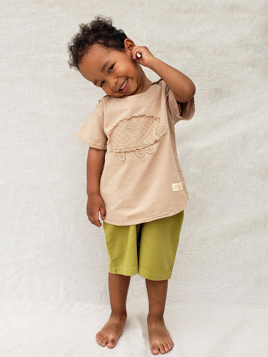 Liten Aventuris Natural Tocuyo Cotton t-shirt for kids. Kirpi is a cute little porcupine embroidered in knitted natural tanguis cotton. Our skilled artisans handcrafted Kirpi with care and attention to detail. Our lovely Kirpi T-shirt is a loose-fitting garment with coconut buttons. The opening on the shoulders makes the kid more comfortable when dressing up. Ethically made in Peru. Bomullskläder, barnkläder, Pojken & flickan tröja, Natural kläder, ekologisk kläder. Skjortor.