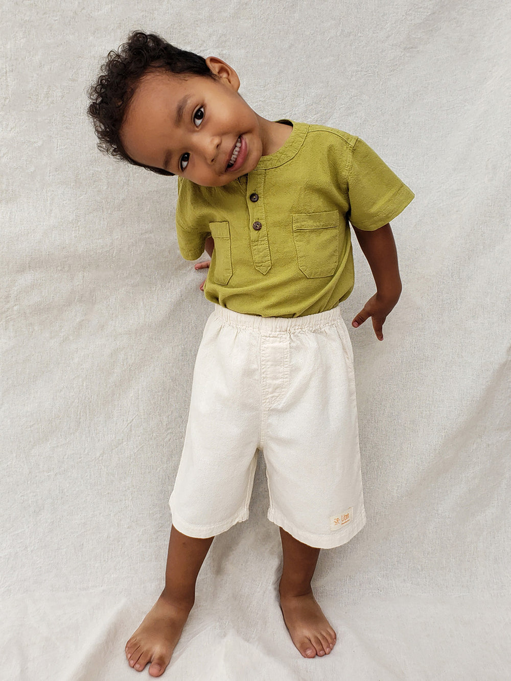 Liten Aventuris Natural Tocuyo Cotton shirt for kids. The Philipo shirt is perfect for a picnic at a lake or a nice morning stroll! This short sleeve shirt with coconut buttons and tunisian collar is casual and chic at the same time. This loose-fitting shirt with two pockets, is comfortable and soft with the skin. Ethically made in Peru. Bomullskläder, barnkläder, Pojken tröja, Natural kläder, ekologisk kläder. Skjortor.