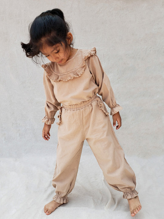 The Siri Pants are elegant and comfortable at the same time. These bloomer pants with ruffles at the bottom are perfect for a walk on the beach or a nice play date at the park. The Siri Pants bring two pockets with knitted cotton ruffles on them. It adds a nice artisanal touch. Beautiful, chic, and charming!  Make the perfect match with the Siri blouse. 100% Natural Peruvian Tocuyo Cotton. Perfect for girls. Barnkläder, Bomullskläder, Natural kläder. Flicka kläder. Barn Byxor.